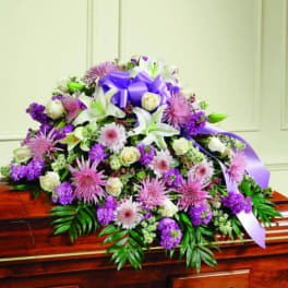 Purple and white floral casket spray with a lavender ribbon