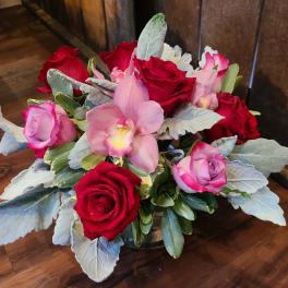 Bouquet of red and pink roses with a pink orchid in a low vase