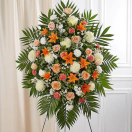 Standing floral spray with orange lilies, peach roses, and white blooms