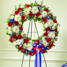 Circular floral wreath of red, white, and blue flowers on an easel