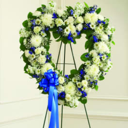 Heart-shaped white and blue floral wreath on an easel with a blue ribbon