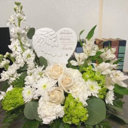 White floral sympathy arrangement with roses and lilies around a memorial plaque