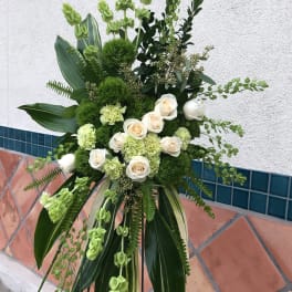 Tall green and white floral standing arrangement with roses and carnations