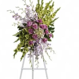 Standing floral spray with purple roses and green orchids on an easel