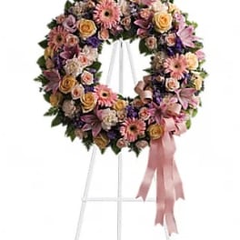 Floral wreath on a white stand with pink ribbon