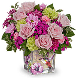 Pink roses and mixed blooms in a square glass vase with bird artwork