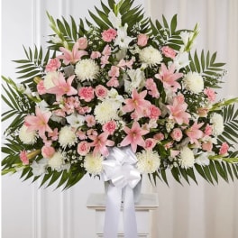 Large pink and white funeral spray with lilies and roses on a stand