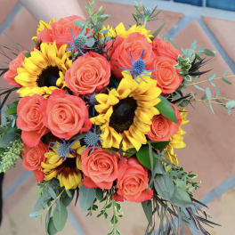 Bouquet of coral roses and yellow sunflowers with greenery