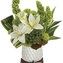 White lilies and green tropical flowers in a white vase