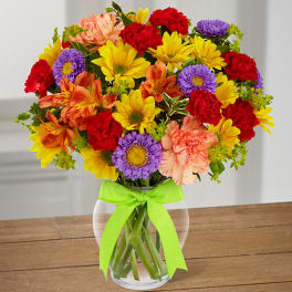 Colorful mixed bouquet in a clear glass vase with a green ribbon