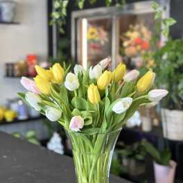 Bouquet of yellow, white, and pink tulips in a clear glass vase