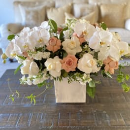 White orchids and peach roses in a square vase