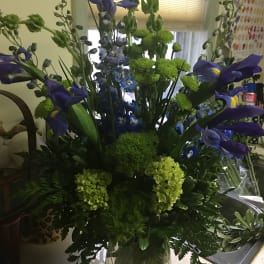Blue iris and green flowers in a clear glass vase