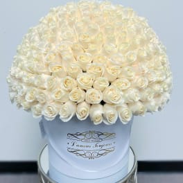 Large dome of cream roses arranged in a white hat box on a small table