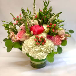 Pink and white flower arrangement with hydrangeas and roses in a clear glass cylinder vase
