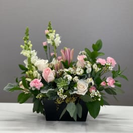 Pink and white floral arrangement in a black container