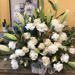 White roses and lilies arranged with carnations and ribbon