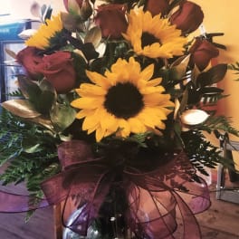 Bouquet of yellow sunflowers and burgundy roses in a glass vase