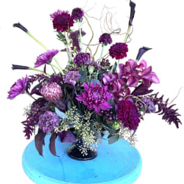 Purple floral arrangement with orchids and calla lilies in a black vase