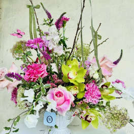 Pink and white floral arrangement in a white vase with tall branches