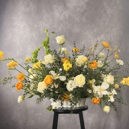 Large yellow and white floral arrangement in a white container