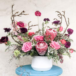 Pink and purple floral arrangement in a white vase