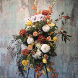 Standing floral spray with orange, yellow, white, and red blooms