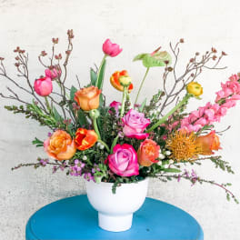 Mixed bouquet of roses, tulips, and snapdragons in a white vase
