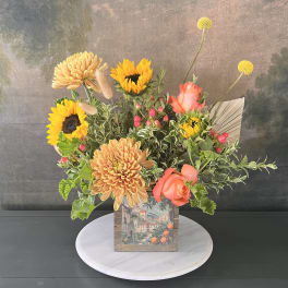 Mixed bouquet with sunflowers, peach chrysanthemums, and coral roses in a decorative box