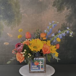 Colorful floral arrangement in a rustic wooden box with roses and sunflowers