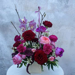 Pink and red floral arrangement in a square vase