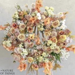 Large pastel floral wreath on a stand with roses and mixed blooms