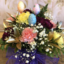 Colorful flower arrangement with glittered Easter eggs and purple ribbon
