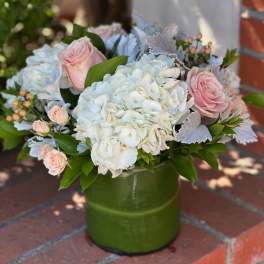 Pink roses and white hydrangeas arranged in a green vase