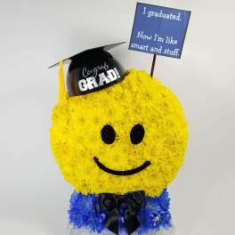 Smiley-face floral arrangement with graduation cap and sign