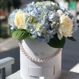 Blue hydrangeas and white peonies in a white hat box with pearl trim
