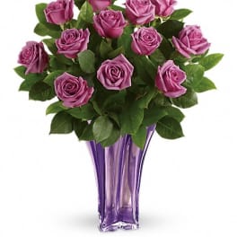Purple roses arranged in a tall purple glass vase