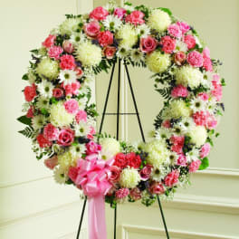 Large floral wreath with pink roses, white daisies, and carnations on an easel
