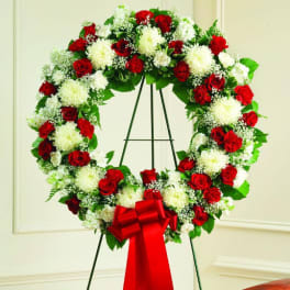 Red and white floral wreath on a stand with a red bow