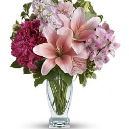 Pink lilies and mixed pink flowers in a clear glass vase