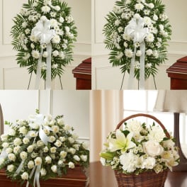White funeral floral arrangements with ribbons and a basket centerpiece
