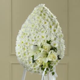 Large white funeral wreath with lilies and roses on a stand