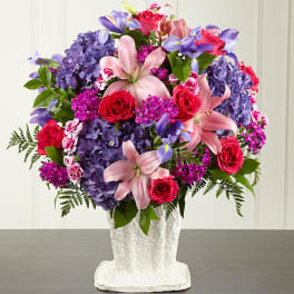 Bouquet of pink lilies, red roses, and purple hydrangeas in a white vase
