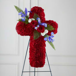 Red floral cross on a stand with blue and white accent flowers
