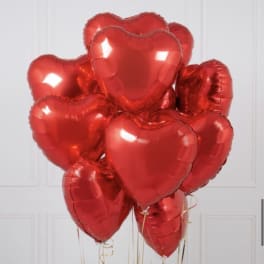 Cluster of red heart-shaped foil balloons with gold ribbons