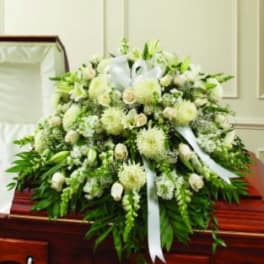 White funeral casket spray with lilies and ribbon