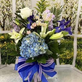 Tall floral arrangement with lilies, hydrangea, and a "Get Well Soon" sign