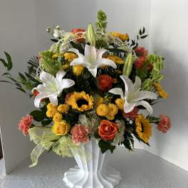 Large mixed bouquet with white lilies, roses, sunflowers, and carnations in a white vase