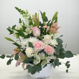 Pink and white mixed flower arrangement in a white basket