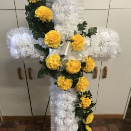 White floral cross with yellow flowers on an easel